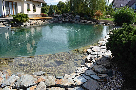 Koupací jezírko se zelení a kamenným břehem