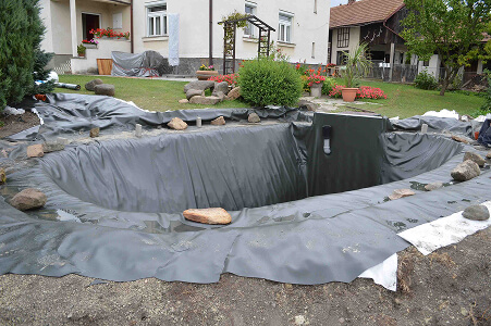 Pokládka geotextilie a jezírkové folie před napuštěním vody