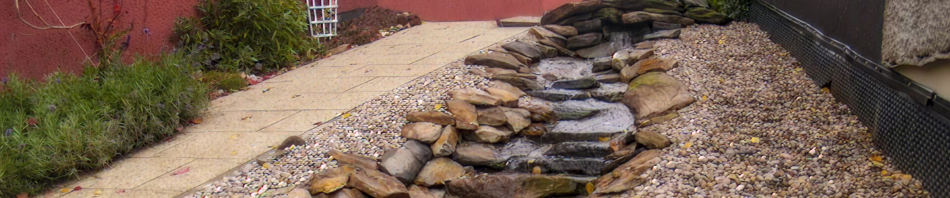 Zahradní vodopád s kamennou zídkou u jezírka