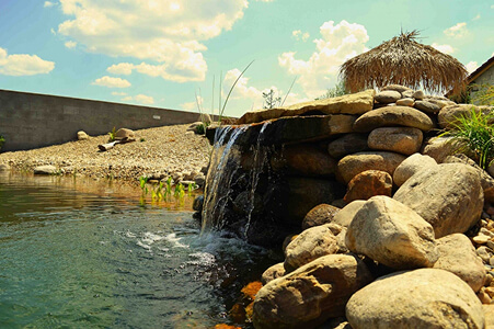 Zahradní vodopád ve svahu obložený přírodním kamenem